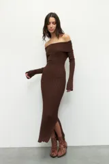 Vestido largo de punto acanalado color marrón, con diseño de hombros descubiertos, mangas largas acampanadas y aberturas laterales en el ruedo.
