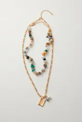 Collar doble dorado con una tira de piedras naturales multicolor y otra cadena de eslabones con dije rectangular liso y perlas colgantes.