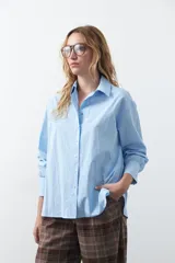 Camisa de corte relajado y diseño clásico, confeccionada en tela de algodón color celeste. Presenta cuello tradicional, cierre frontal con botones y mangas largas con puños rectos.
