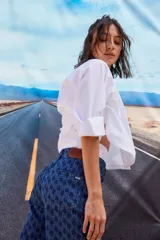 Jean de tiro bajo y corte oversize, confeccionado en denim azul con monograma grabado a láser en toda la prenda. Presenta doble botón metálico en la cintura y diseño de cinco bolsillos.