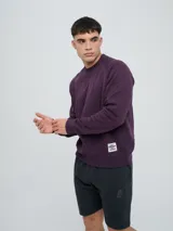 Buzo de felpa bordó, estilo relaxed, con cuello redondo y mangas raglán. Presenta puños y dobladillo acanalados, y una pequeña etiqueta con el logo de Umbro en el lateral inferior.