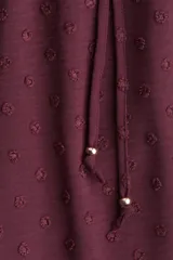 Pantalón ancho de tiro alto color bordó, con textura plumeti (pequeños puntos en relieve) y cintura elástica fruncida con cordón ajustable.