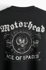 Buzo negro de algodón de peso medio con cuello redondo, hombros caídos y remates acanalados. Presenta un estampado frontal de una calavera rodeada de texto y texto en ambas mangas en tipografía gótica.