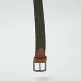 Cinturón verde oliva trenzado con hebilla metálica plateada y detalles en cuero marrón.