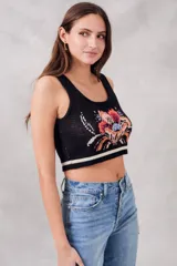 Musculosa corta de punto negra con diseño floral bordado en el frente y rayas horizontales blancas en el ruedo.