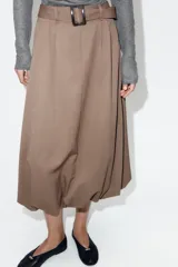 Falda midi de tiro alto en color marrón topo, con diseño abullonado en el bajo gracias a un elástico interior. Presenta pinzas frontales, cierre delantero con cremallera y un cinturón integrado con hebilla a tono.