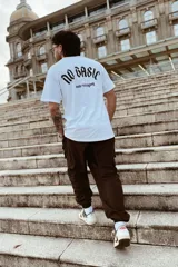 Remera blanca oversize de manga corta, con estampa en la espalda que dice "NO BASIC" en tipografía gótica y "made in uruguay" debajo.