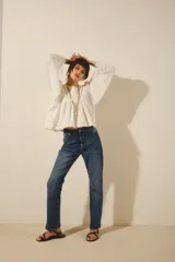 Jean de corte recto y tiro alto, confeccionado en denim azul con un lavado localizado que presenta efecto de bigotes y torceduras. Cuenta con cierre y botón frontal.