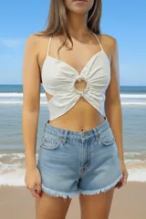 Top blanco con diseño en forma de mariposa, con escote halter y detalle de argolla central con brillos. Posee espalda descubierta y tiras finas que se atan al cuello.