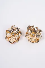 Aros con diseño de flor abstracta en metal dorado, con textura irregular y un cristal central brillante.