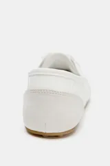 Zapato tipo blucher blanco con puntera y talón en gamuza gris claro, con cordones y suela plana color caramelo.