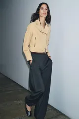 Chaqueta estilo biker de piel de ante 100% color beige, con cuello solapa, manga larga, bolsillos con cremalleras metálicas y bajo ajustable con hebilla. Cierre frontal con cremallera metálica.