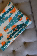 Funda para laptop con estampado geométrico en tonos verde, naranja, blanco y lila.