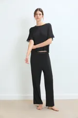 Pijama de dos piezas color negro, compuesto por una remera de manga corta con detalles de encaje en los bordes y un pantalón largo de corte recto con cintura elástica decorada con encaje.