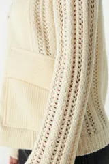 Campera marrón de lana fina sin teñir, con cierre frontal, mangas largas y laterales en tejido de punto. Presenta bolsillos frontales tipo parche.