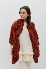 Chal de lana color marrón con diseño envolvente, decorado con volados aplicados en toda la superficie que aportan textura y movimiento.
