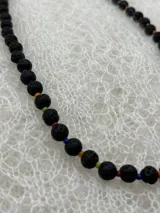Collar corto de cuentas redondas de piedra de lava negra, con detalles de cuentas pequeñas de colores entre cada cuenta de lava.