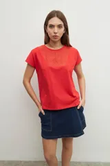 Remera de manga corta color rojo vibrante, con cuello redondo y un panel frontal con bordados calados (ojales) en forma de V invertida.
