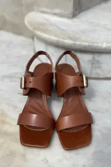 Sandalias de cuero color marrón, con punta cuadrada, tira ancha sobre los dedos, tira al tobillo con hebilla dorada y taco bloque de 7 cm.