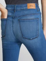 Pantalón de jean azul oscuro, tiro alto, corte super skinny y acabado liso.