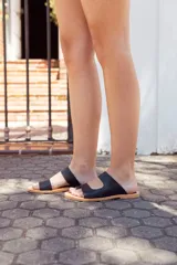 Sandalias negras de cuero con dos tiras anchas sobre el empeine y suela plana.