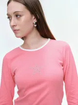Remera de manga larga entallada, confeccionada en algodón elastizado. Presenta cuello redondo en color blanco a contraste y un detalle de estrella central compuesta por brillos.