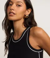Musculosa de rib en color negro, con diseño ajustado al cuerpo, cuello redondo y frisos contrastantes blancos en el escote y las sisas.