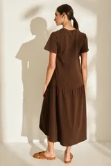 Vestido midi color crudo de manga corta, con corte en la cintura y falda holgada con volados y detalle de pequeño bordado de hongo en el pecho.