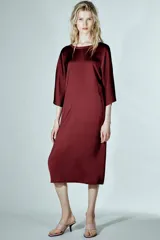 Vestido midi de Zara Woman Collection confeccionado en viscosa satinada, color bordó. Presenta cuello barco, mangas por debajo del codo y bajo recto, con detalle de lazo fino en la parte posterior del cuello.