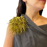 Broche de tela con diseño de flor voluminosa en color verde oliva, confeccionado con múltiples tiras delgadas que crean un efecto de textura y movimiento.