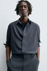 Camisa de corte relajado, color azul marino, con cuello solapa, manga larga con puños abotonados y cierre frontal de botones.