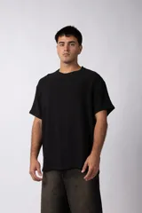 Remera de lino color negro, con cuello redondo, mangas cortas y corte holgado. Presenta una textura rústica y entramada característica del tejido de lino.