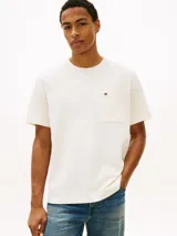 Remera Tommy Hilfiger de corte amplio y estilo urbano, confeccionada en punto de malla de mezcla de algodón en color blanco. Presenta cuello redondo, hombros ligeramente caídos y un bolsillo de parche en el pecho con el logo bordado.