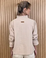 Blusa blanca de algodón con escote en V y cuello mao. Presenta mangas largas abullonadas con puños acampanados y fruncidos.