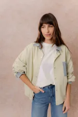 Camisa Kori de calce relajado color verde claro, con cuello clásico, puños, cartera y bolsillo frontal con aplique en denim a contraste. Cierre frontal con broches metálicos y mangas largas.