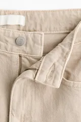 Jean de tiro alto y piernas amplias confeccionado en denim de algodón con diseño de cinco bolsillos y cierre frontal con botón y cremallera.