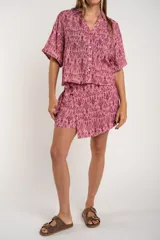 Short pollera color rosa con estampado abstracto en tonos borgoña y lazo lateral.