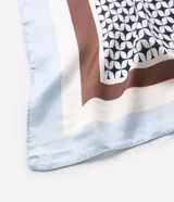 Pañuelo de satén con diseño cuadrado, estampa geométrica en blanco y negro en el centro, marco marrón y bordes celestes.