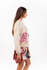 Sweater de lana merino color beige, tejido a mano con diseño holgado, cuello redondo y bordados artesanales de ranas y detalles coloridos.