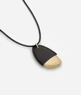 Collar largo con cordón negro y colgante de forma orgánica, mitad negro y mitad dorado. El colgante está hecho de poliuretano, zinc y hierro.
