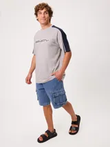 Remera negra de manga corta con diseño deportivo, parte superior de las mangas en color gris con ribete blanco y estampa frontal con la marca Rusty.