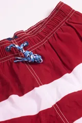 Short de baño azul con franjas horizontales en celeste y azul claro. Cuenta con cintura elástica ajustable con cordón, dos bolsillos laterales y uno trasero.