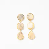 Caravanas colgantes con tres piezas geométricas de resina en tonos beige y gris, engarzadas en metal dorado.