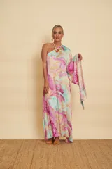 Vestido largo con diseño marmolado en tonos celestes, rosados y amarillos, de corte asimétrico con un solo hombro y manga larga acampanada.