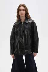 Campera de eco-cuero negro con acabado brillante, cuello camisero, cierre frontal completo y diseño de corte holgado.