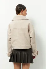 Tapado corto gris de paño, con cuello solapa grande, bolsillos de parche con solapa y mangas largas con puños anchos con presilla y aro metálico.