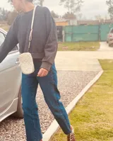 Cartera pequeña negra con diseño acolchado, cierre de cremallera y correa de mano. Incluye tarjetero interno.