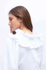 Blusa blanca de algodón con cuello alto fruncido con volados y mangas abullonadas con puños elásticos.