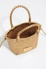 Bolso mini trenzado color dorado, con doble asa corta de mano y correa larga para el hombro. Incluye parche con logo grabado en el frente.