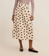 Pollera midi evasé de tricolina color beige con lunares negros, cintura ancha con elástico en la espalda y algodón certificado BCI.